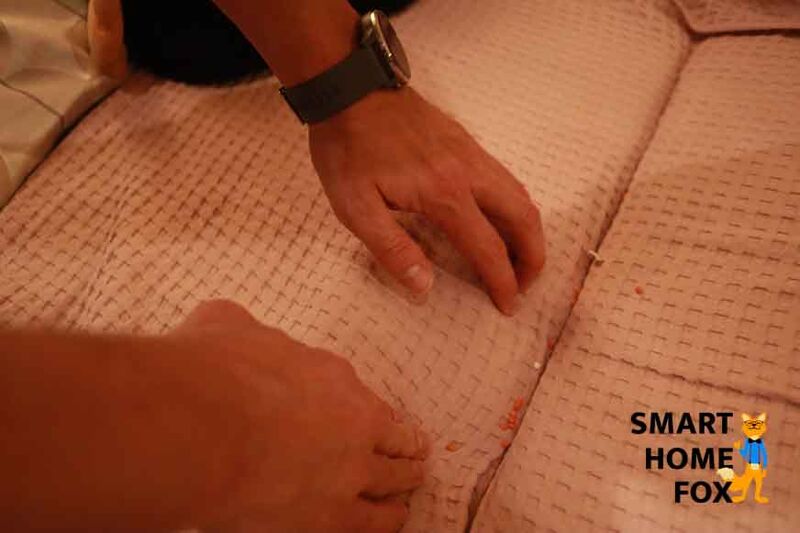 Man sieht Dreck im Zwischenraum zwischen Polstern eines Sofas.